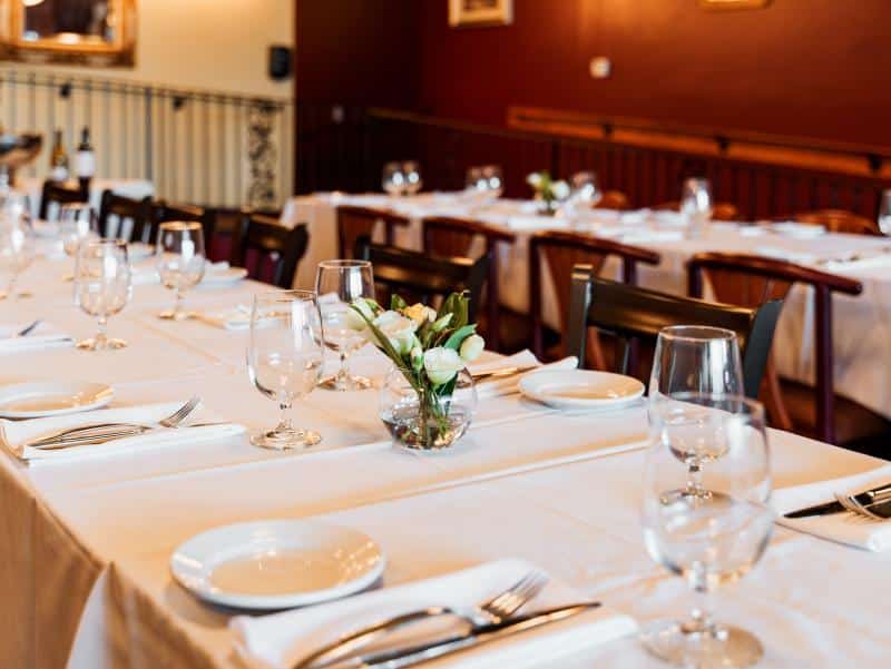private dining table set with glasses plates and vase with white flowers