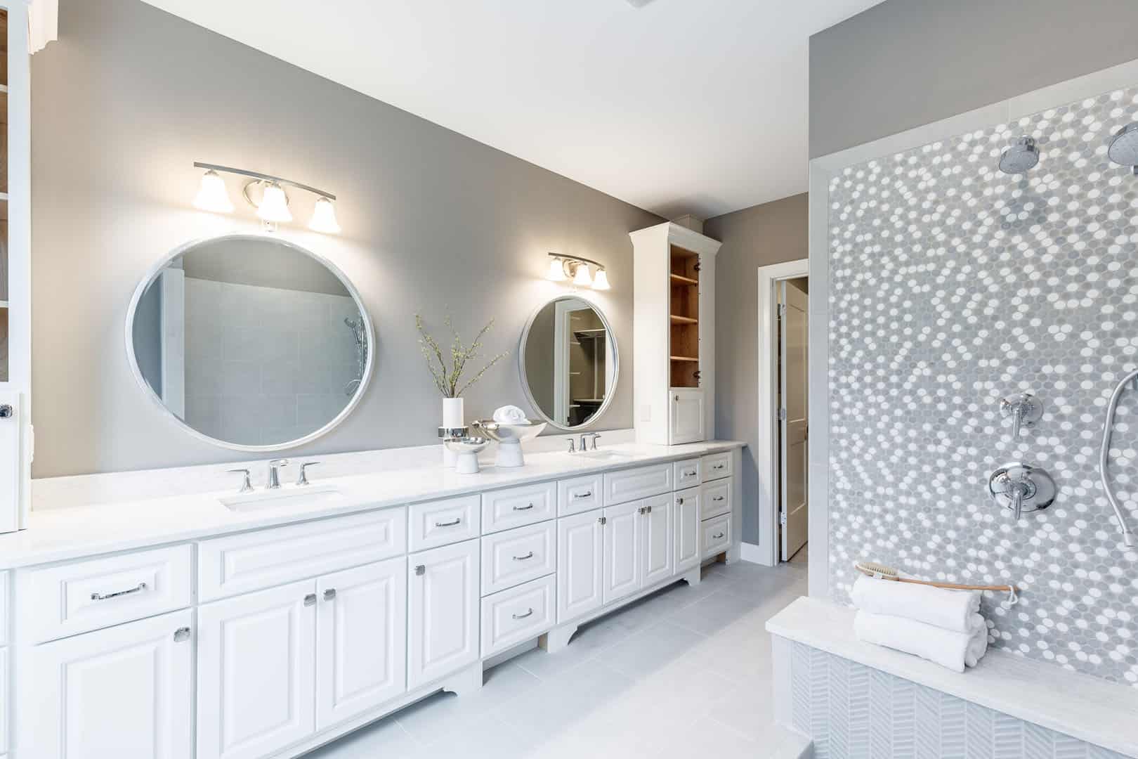 large bathroom with tile shower and white double vanity