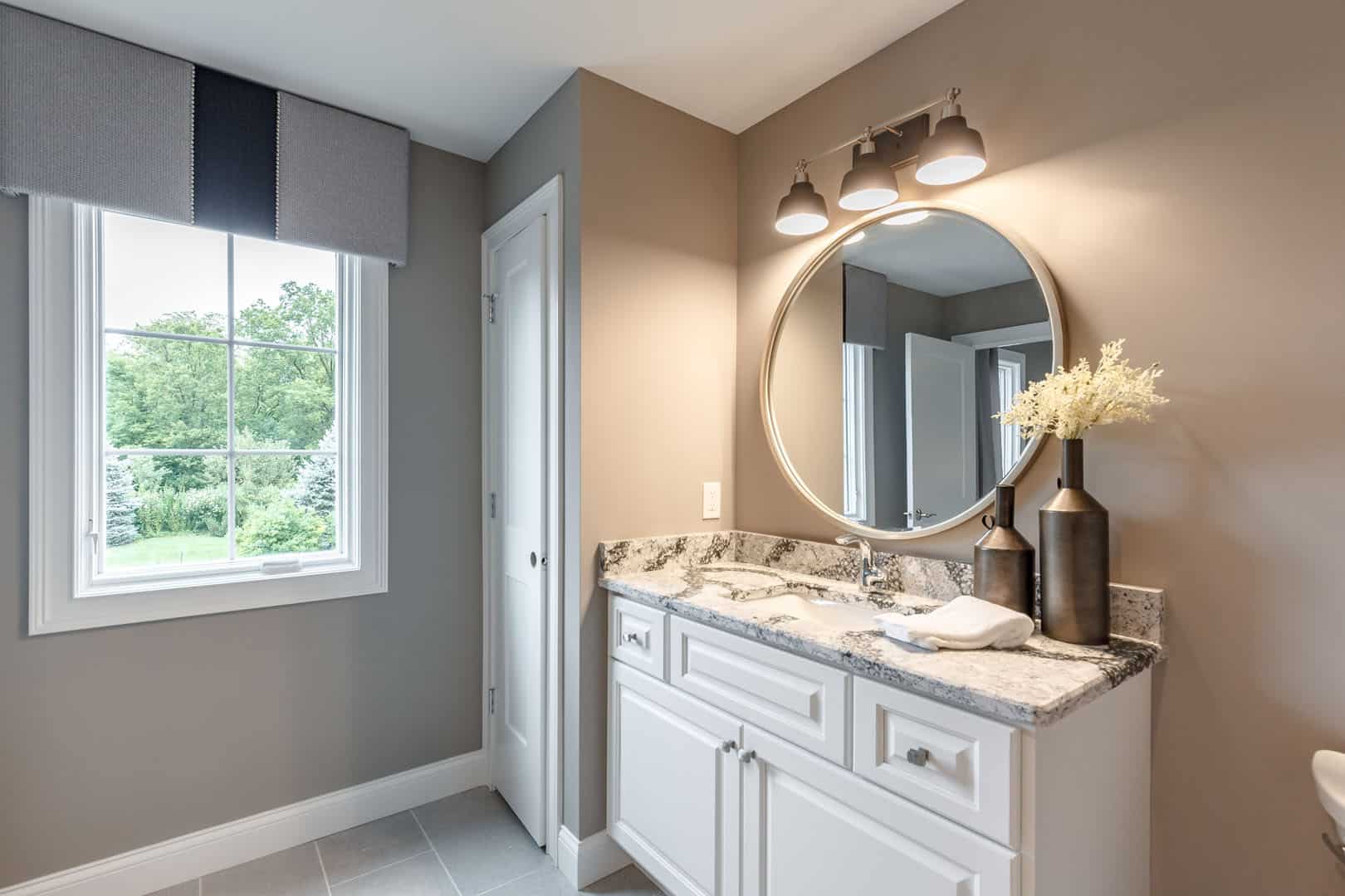 bathroom with round mirror above white vanity