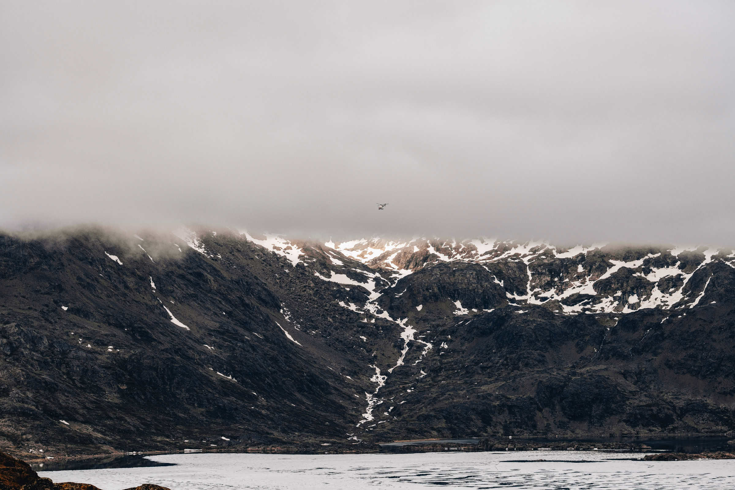 Helicopter disappearing into the fog. Photo by Filip Gielda - Visit East Greenland