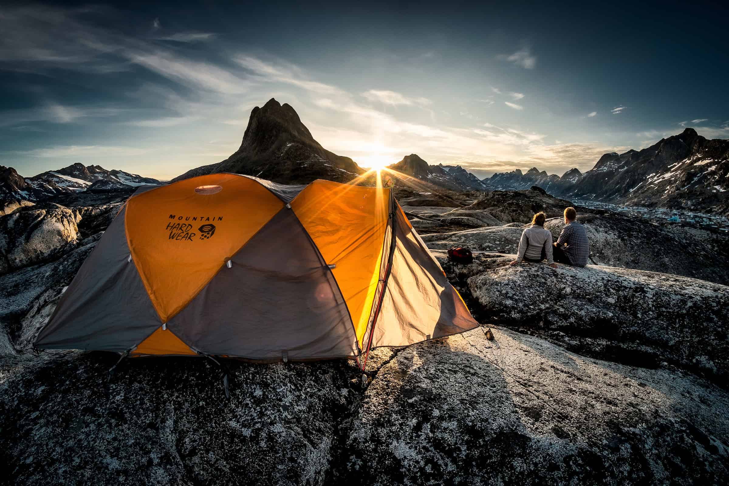 Sunset over two hikers near a tent camp at Qernertivartivit in East Greenland. Photo by Mads Pihl - Visit Greenland