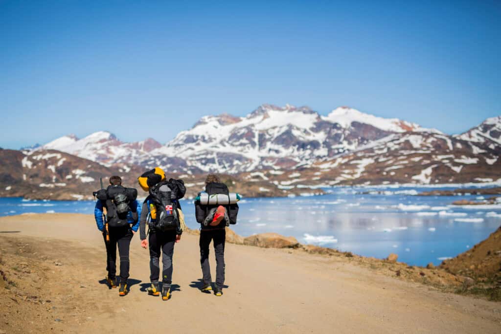 Three hikers making their way out of Tasiilaq along the fjord.