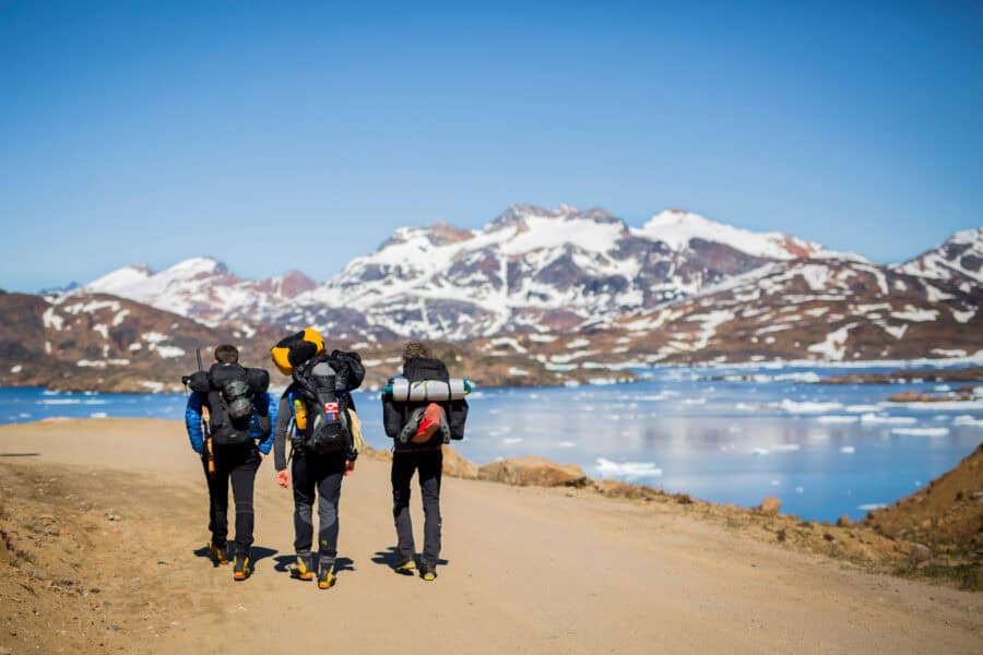 Three hikers making their way out of Tasiilaq along the fjord.