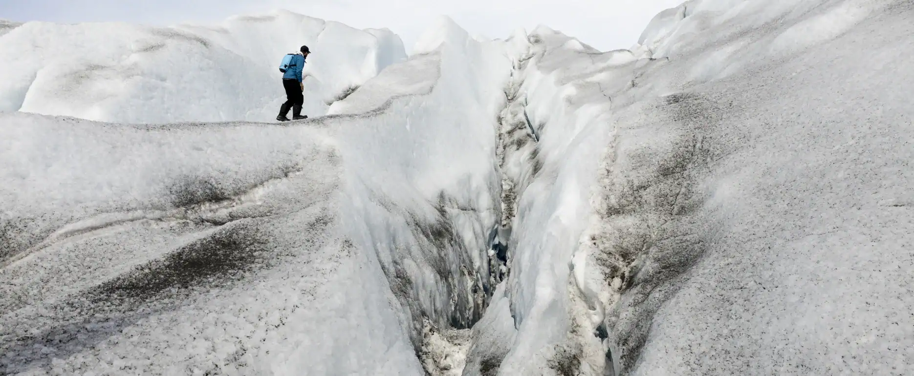 Adventurer walking along a glacial crevasse in East Greenland.