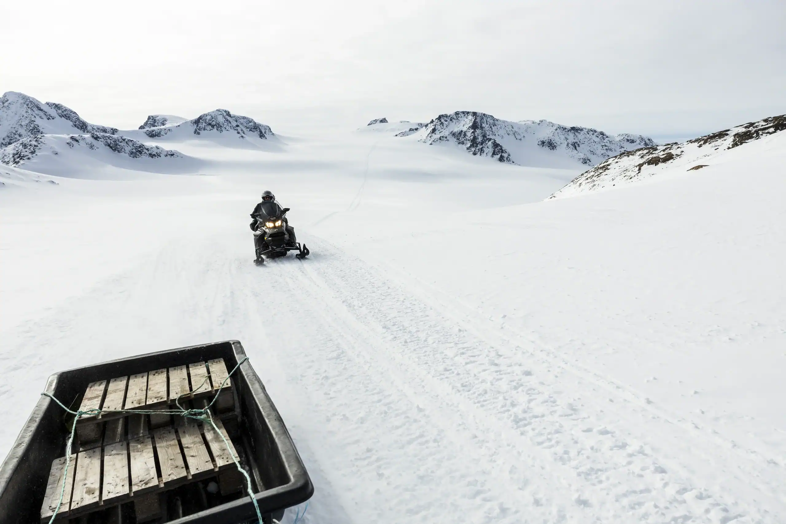 Snowmobile Towing a Sled Through East Greenland’s Pristine Arctic Snowfields.