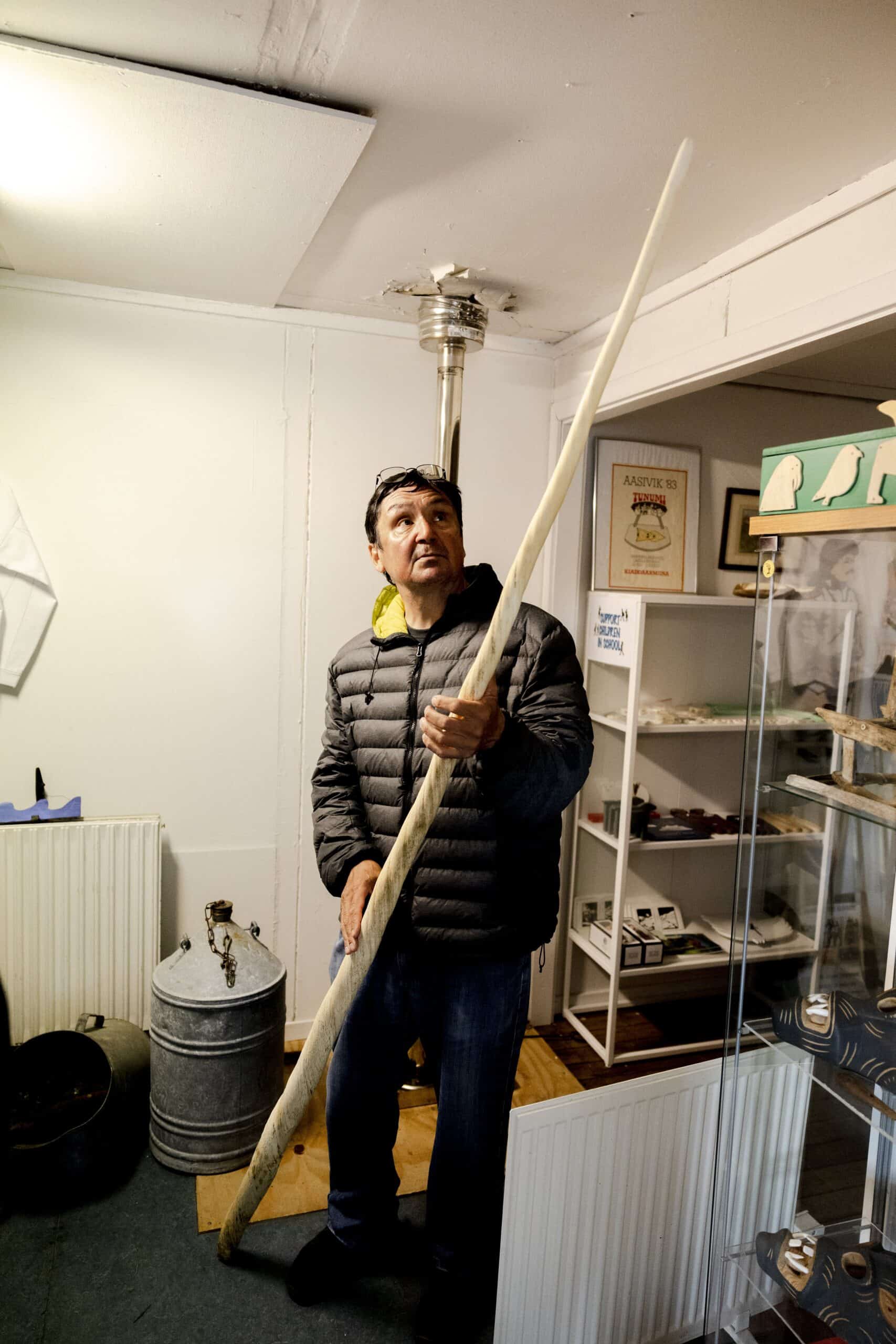 Guide at Kulusuk museum presenting narwhal tusk.