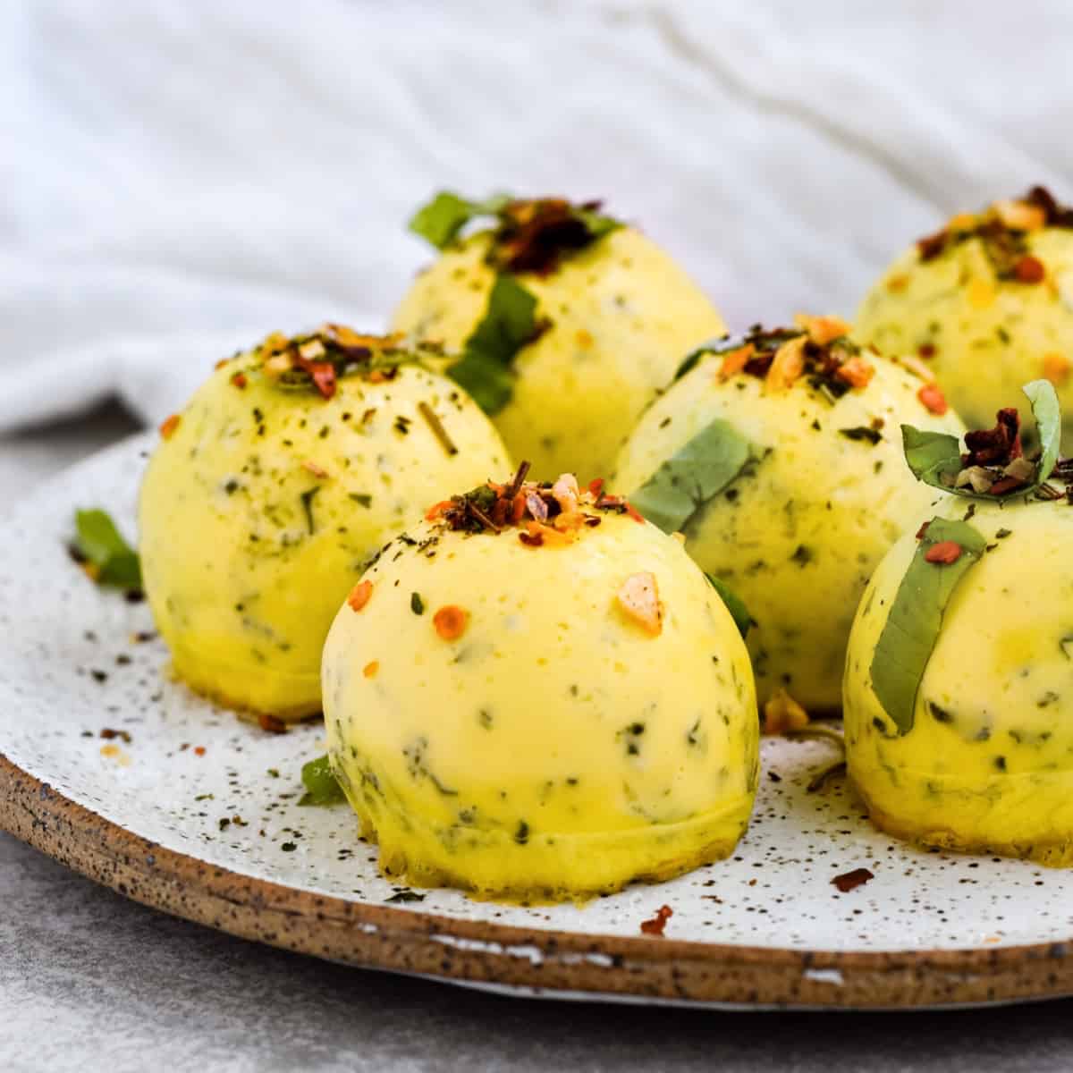 This is a side view of the copycat starbucks instant pot egg bites on a speckled plate topped with crushed red pepper flakes and basil.
