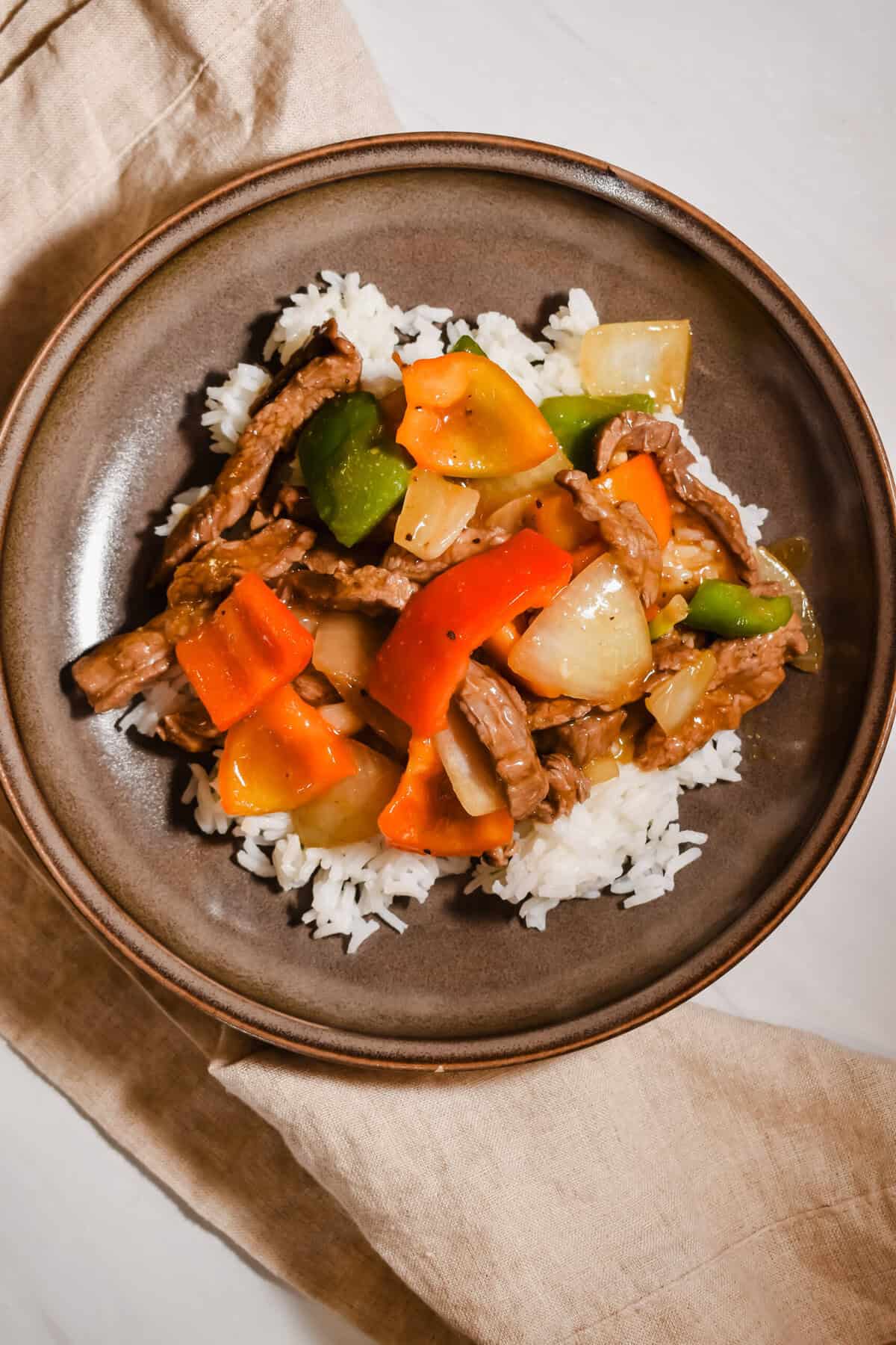 Pepper steak stir fry with bell peppers and served over rice.