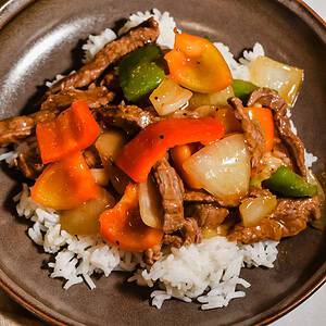 Close up of pepper steak stir fry served over rice.