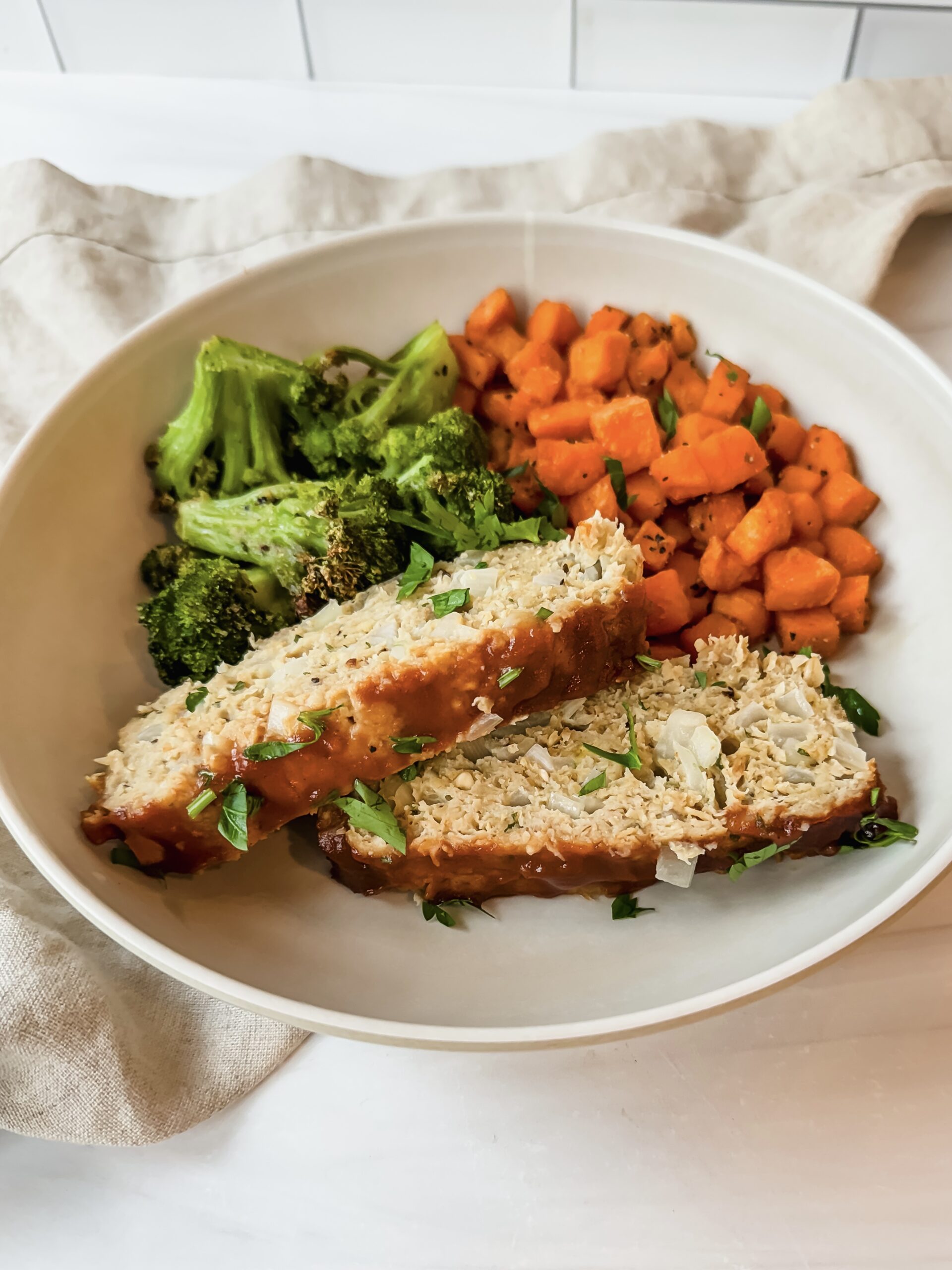 This is a close up of my chicken meatloaf recipe with oatmeal served with diced air-fried sweet potatoes and broccoli in a plate. 