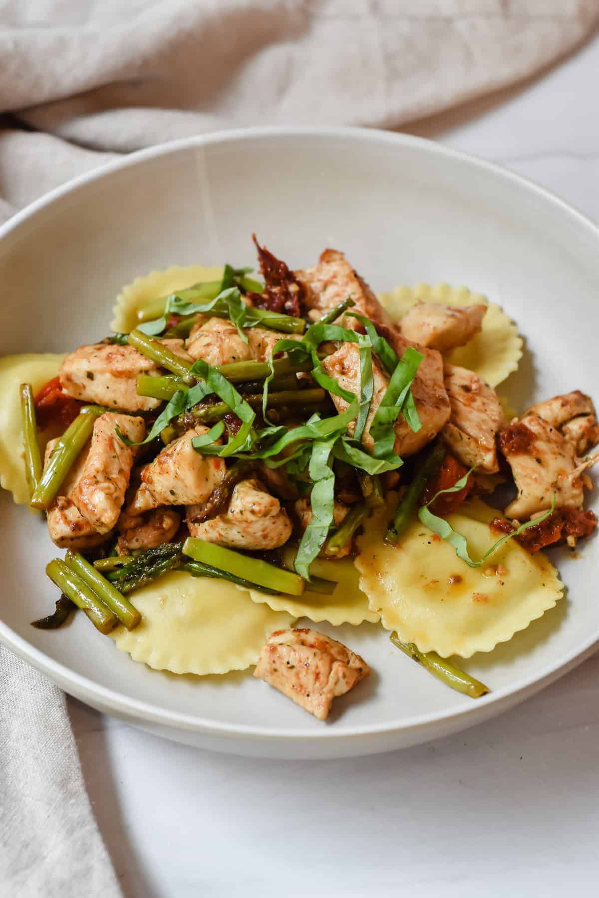 This is a side view close up of my beautiful lemon ravioli topped with the chicken, sun-dried tomatoes, asparagus in a browned garlic sauce with lemon and fresh basil.