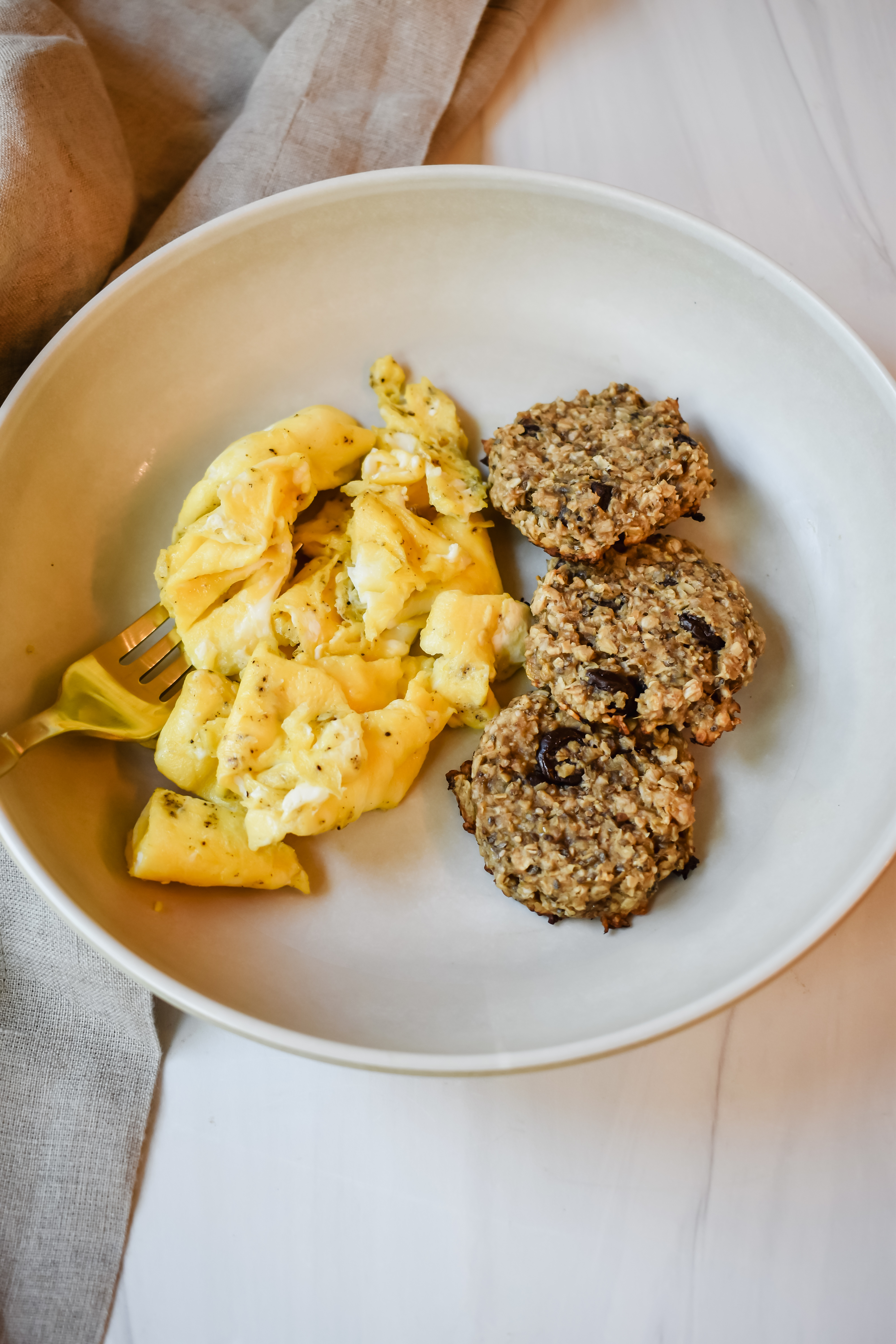This is a top view of my delicious 4 ingredient breakfast cookies in a shallow bowl with some scrambled eggs for extra protein