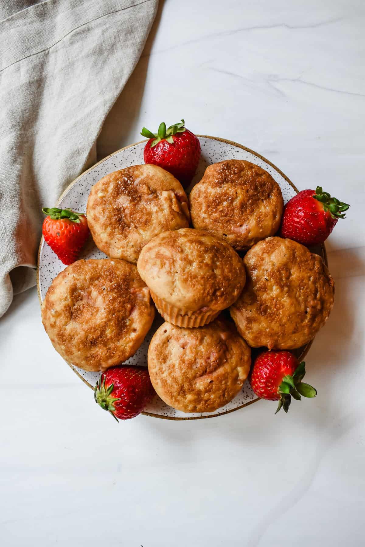 This is a top view of my cottage cheese strawberry muffins with fresh strawberries on a plate.