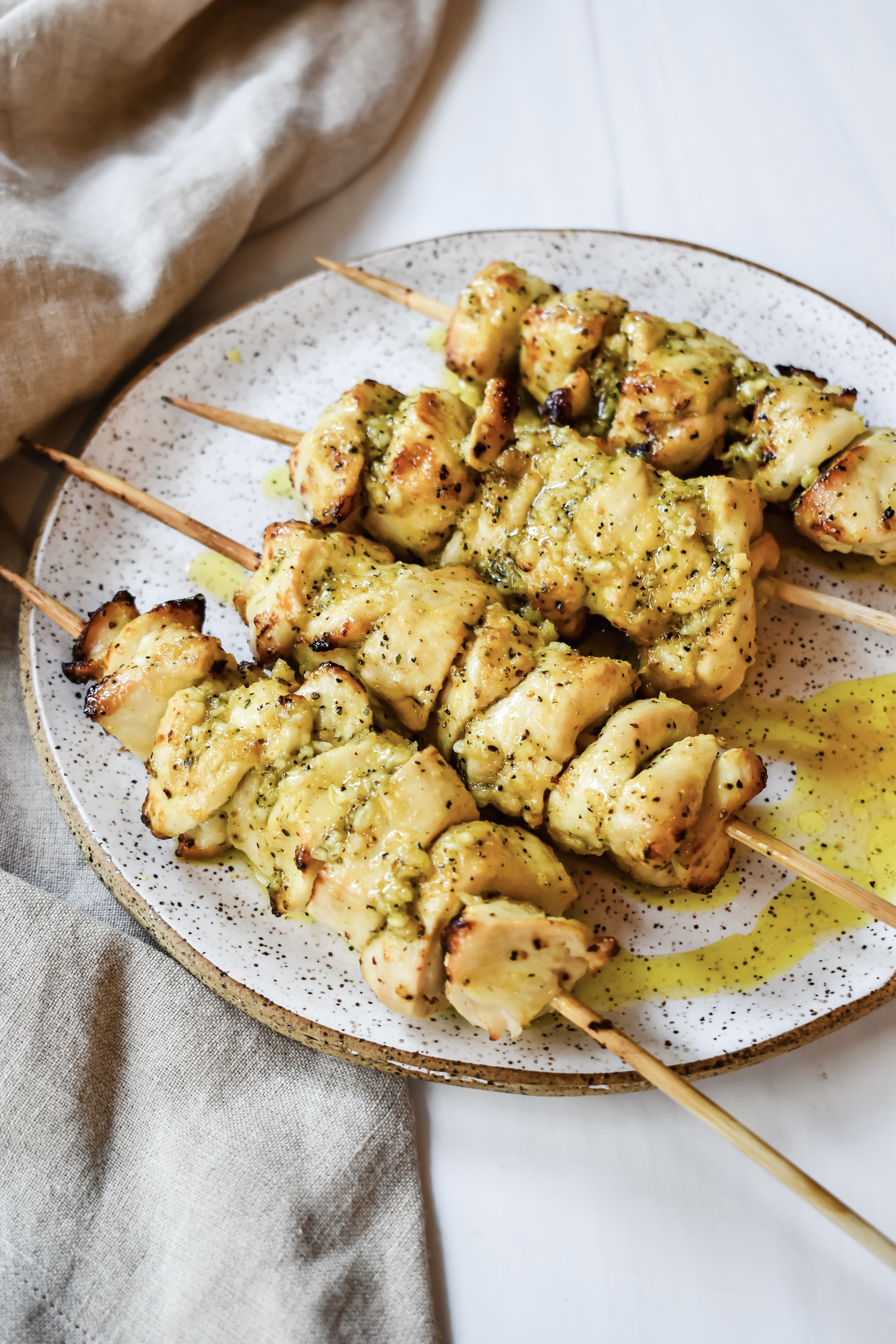 This is a close up side view of my lemon pepper chicken skewers on a plate with melted butter on top.