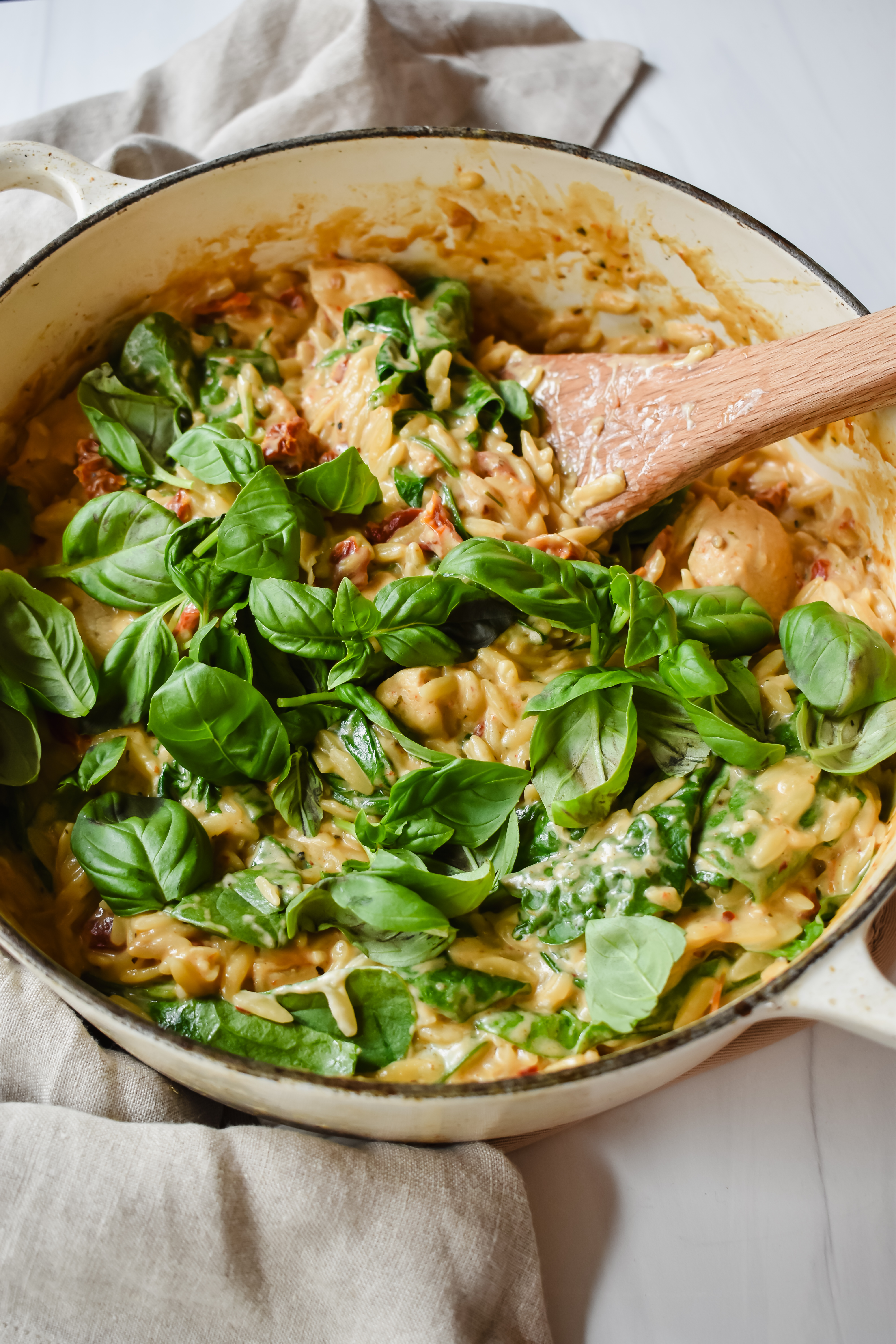 This is a side view close up of my one pot creamy lemon chicken orzo in the pot with fresh basil on top. 