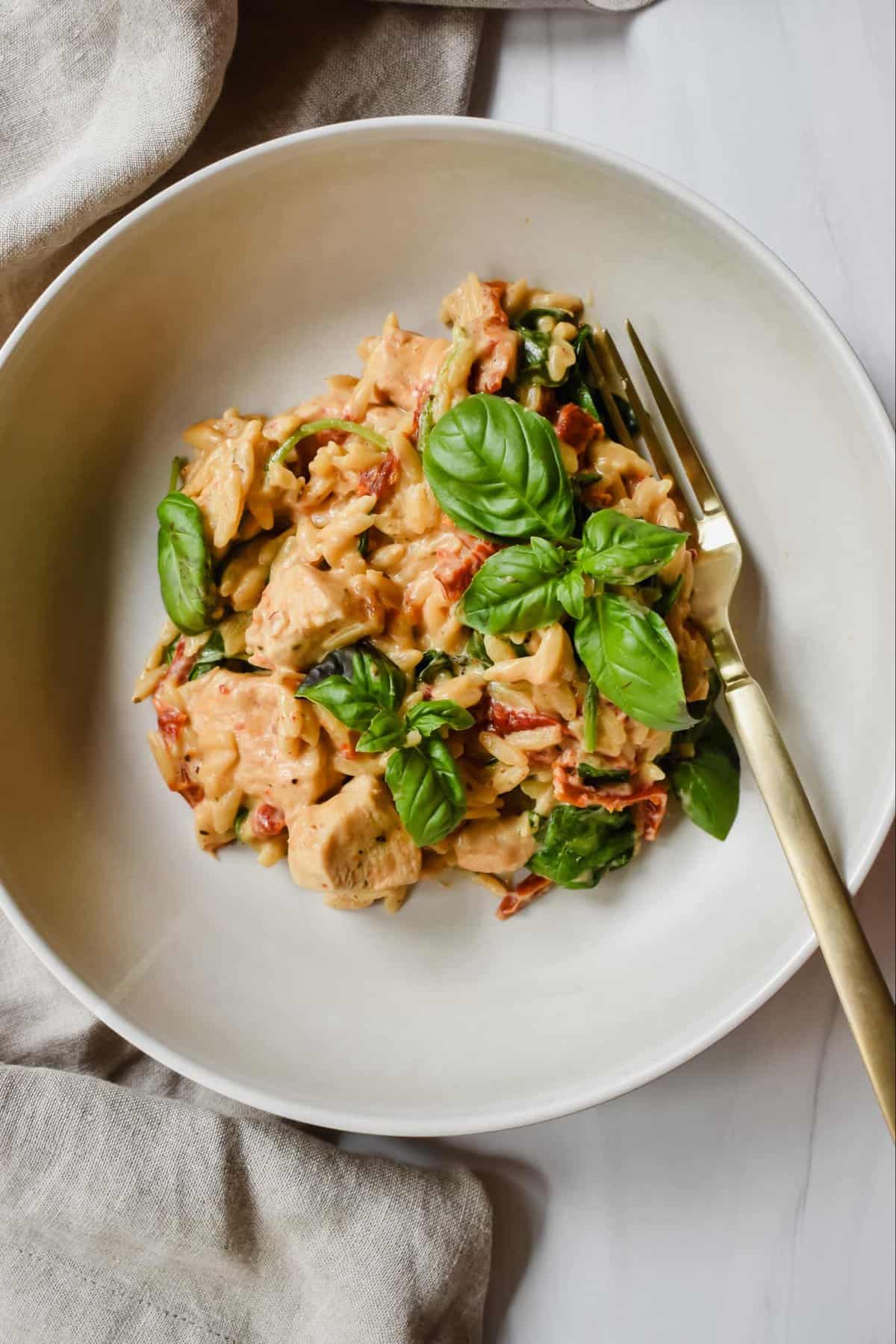 this is an overhead view of my orzo in a bowl with a golden fork.