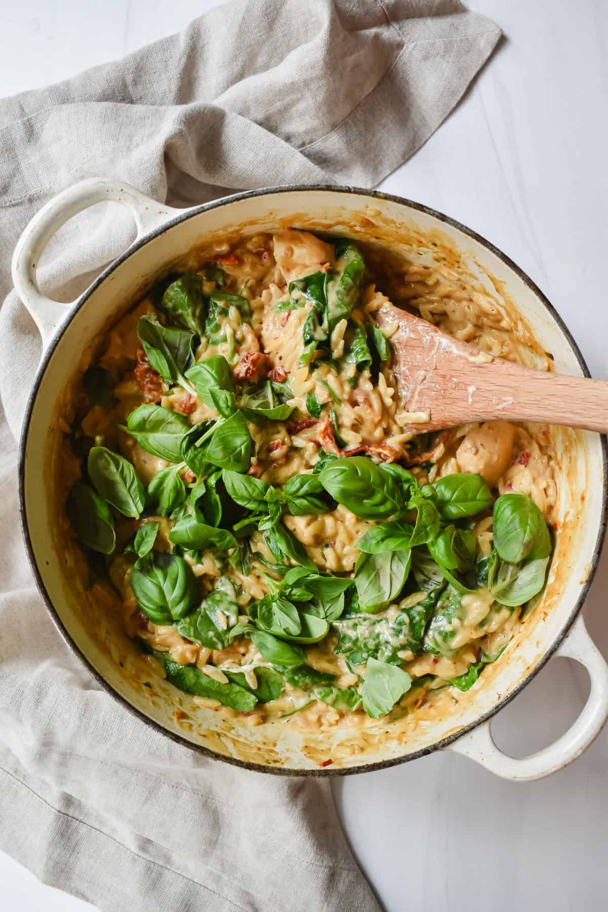 this is an overhead view of my one pot chicken lemon orzo in the dutch oven topped with fresh basil and ready to serve. 