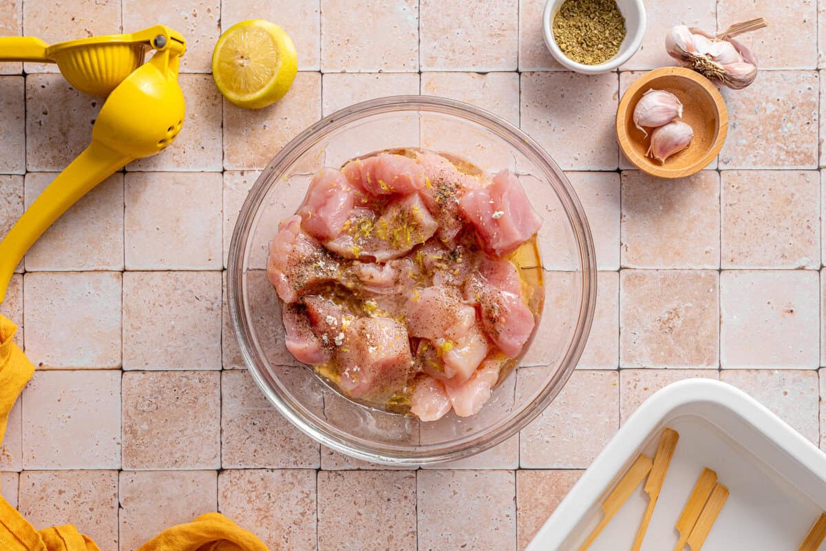 this shows me adding all of the chicken into a bowl with the oil, lemon and seasonings 