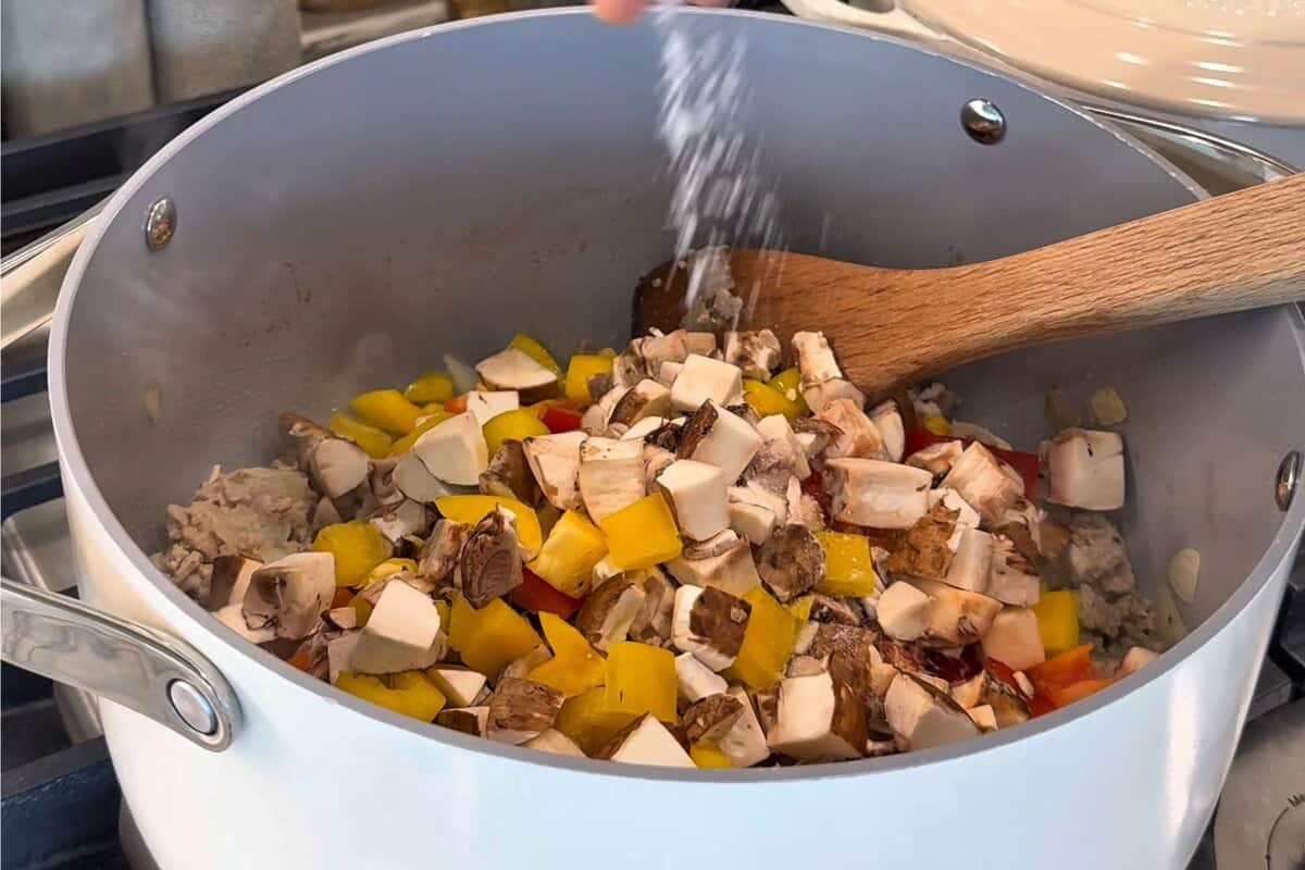 this shows me adding the veggies to the pot with some salt