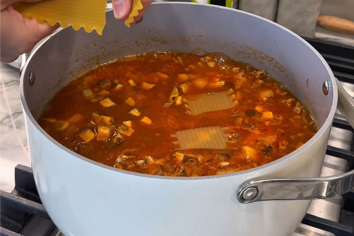 this shows me breaking the pasta pieces into the soup 