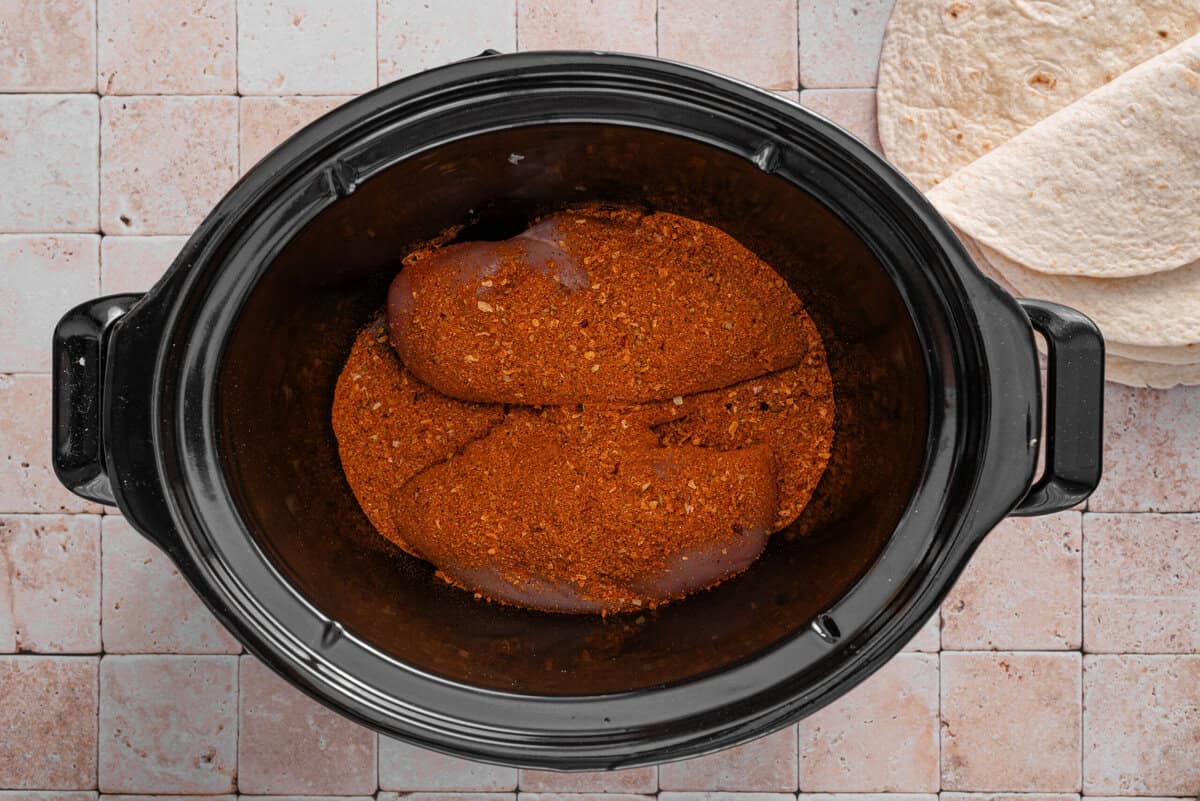 this shows me adding seasoning on to the chicken breasts in the slow cooker