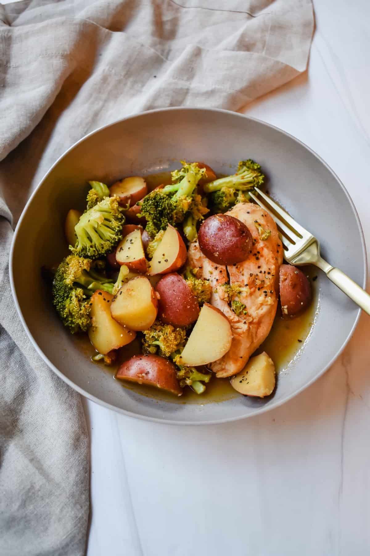 This is a side view close up of my crockpot lemon chicken with potatoes and broccoli in a bowl.