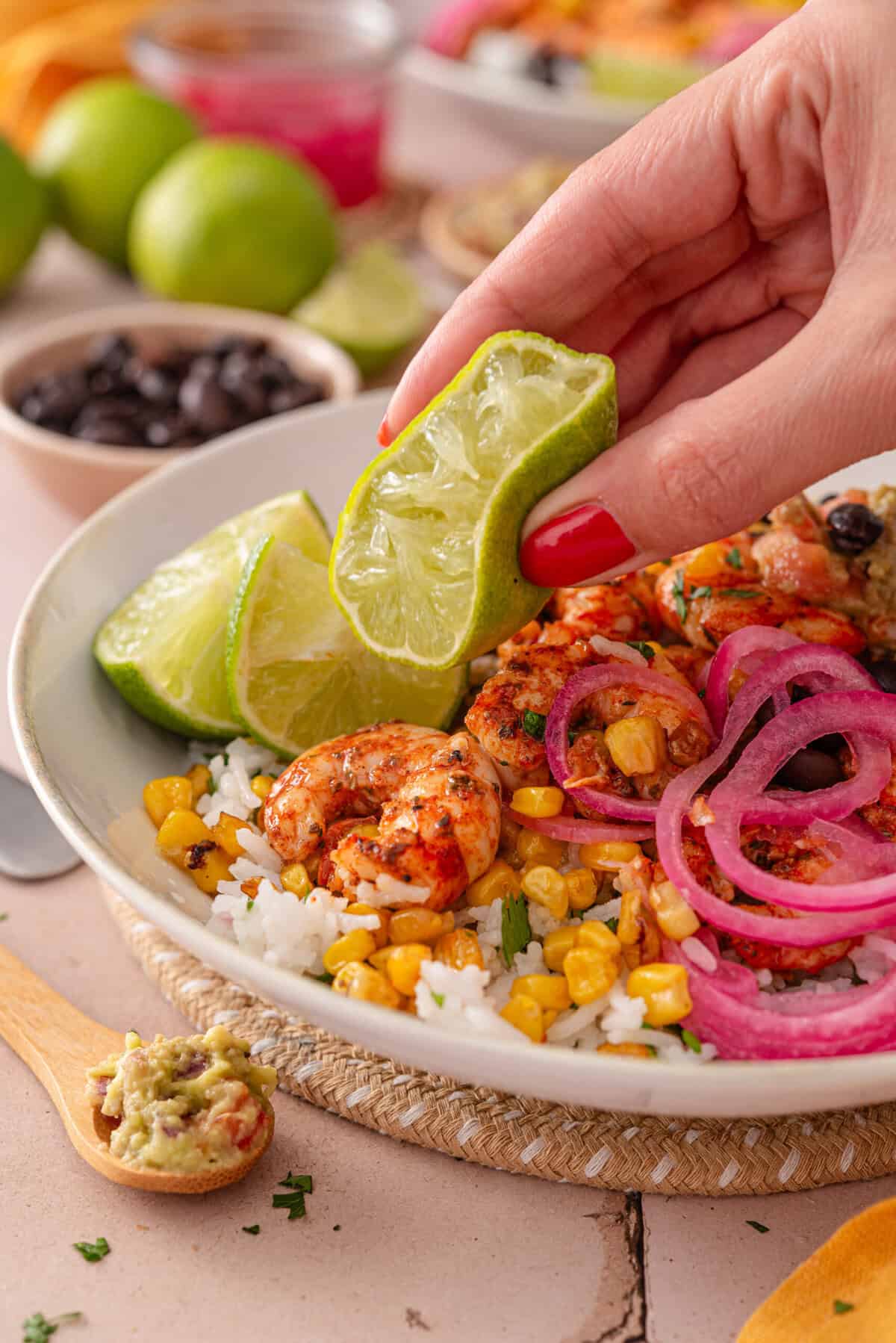 this is a side view close up of my chili lime shrimp bowls with me squeezing the lime on top.