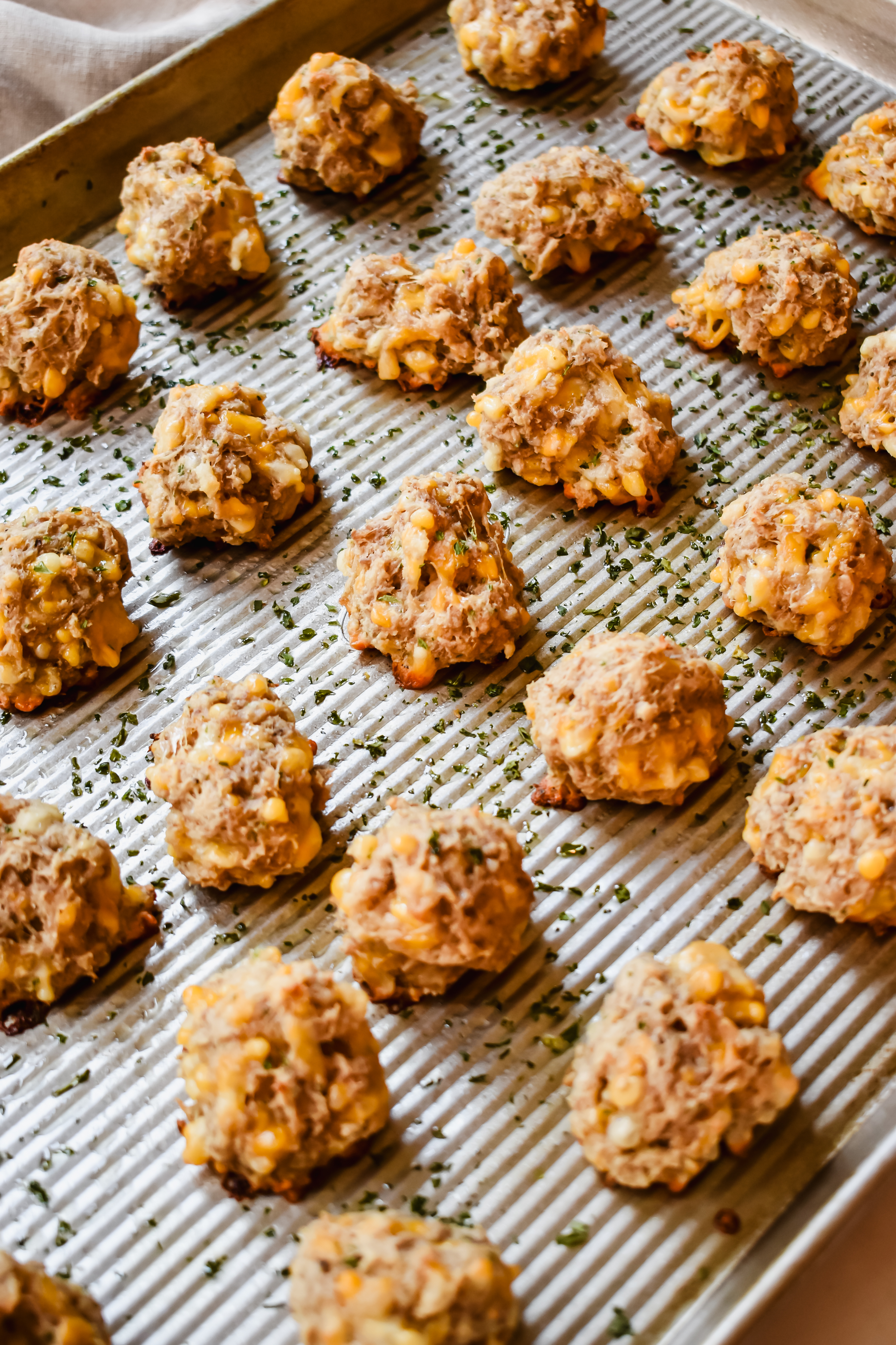 this is a side view close up of the sausage biscuit balls on a sheet pan