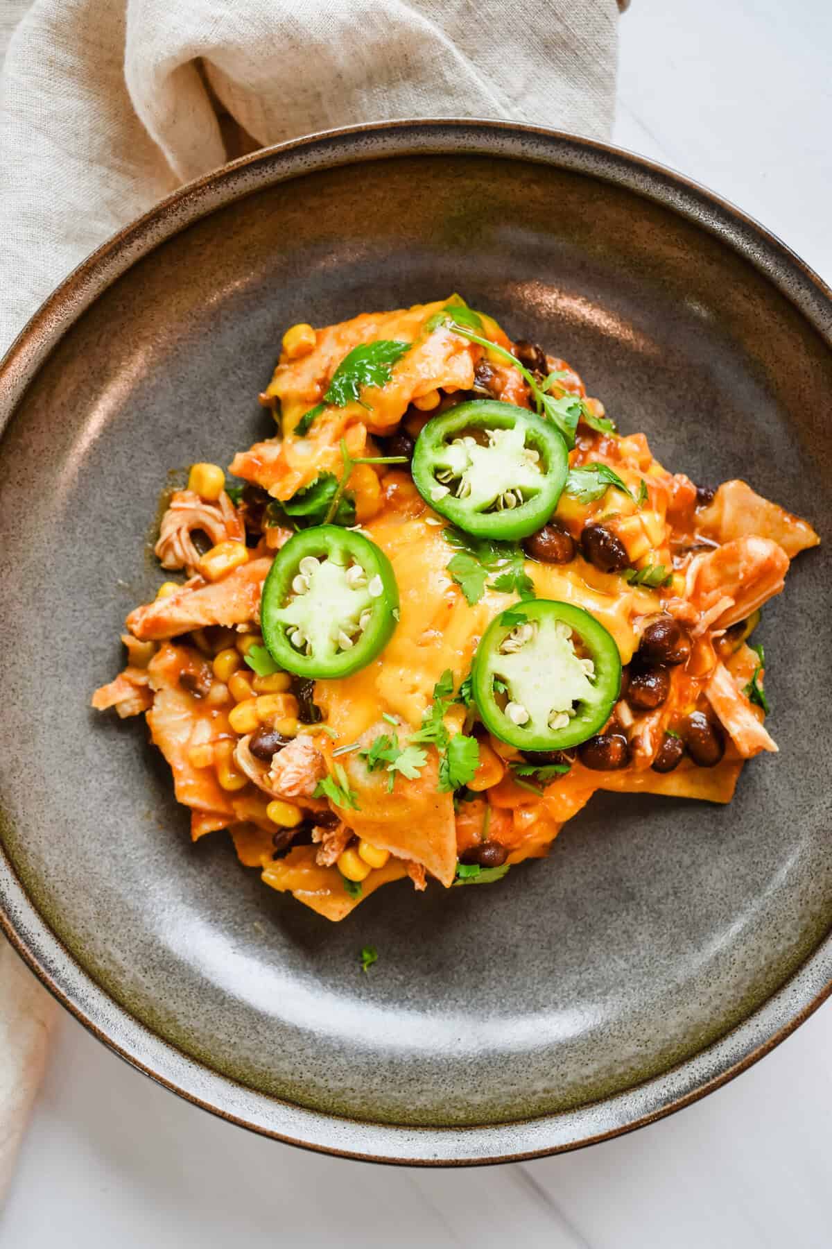 this is an overhead view of the chicken enchilada casserole with jalapenos on top in a bowl 