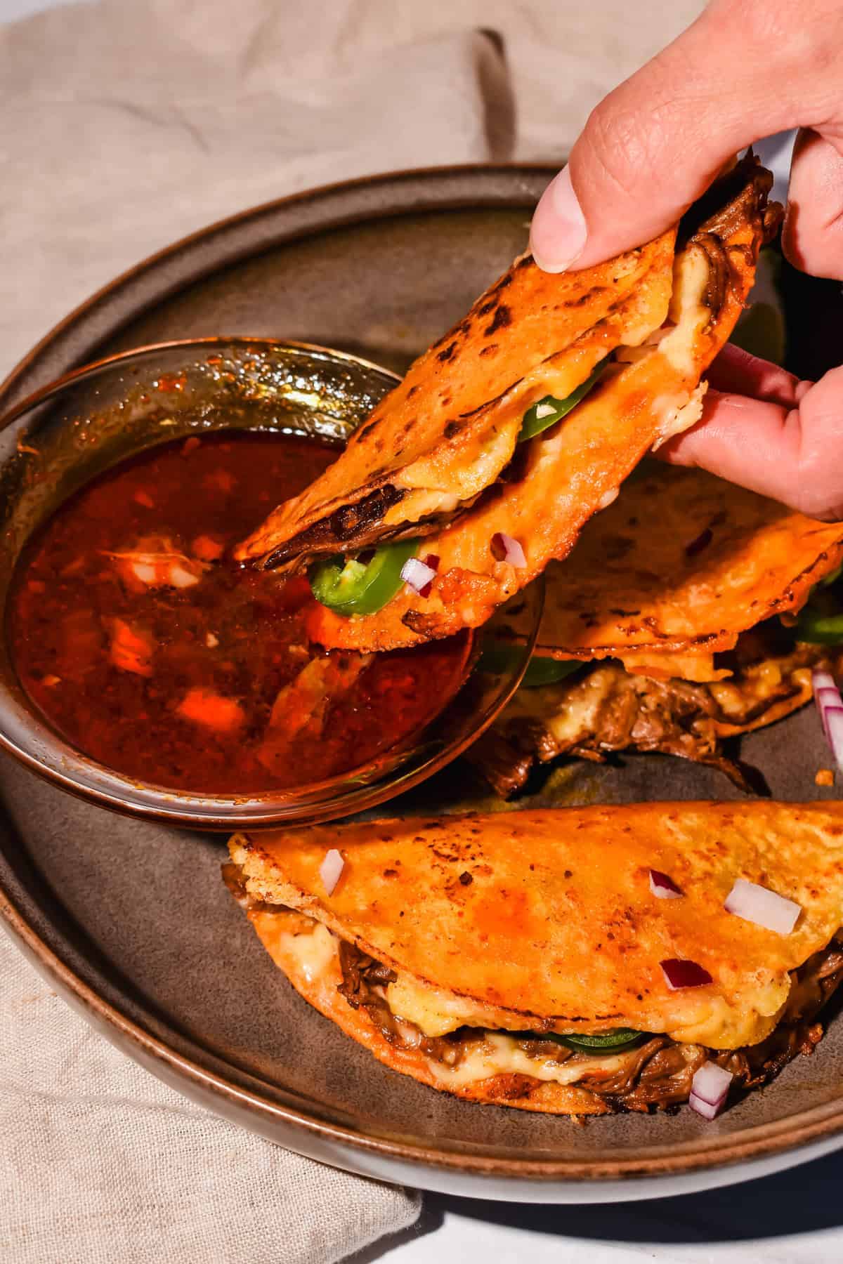 this shows me dipping my birria bomb tacos into the consume 