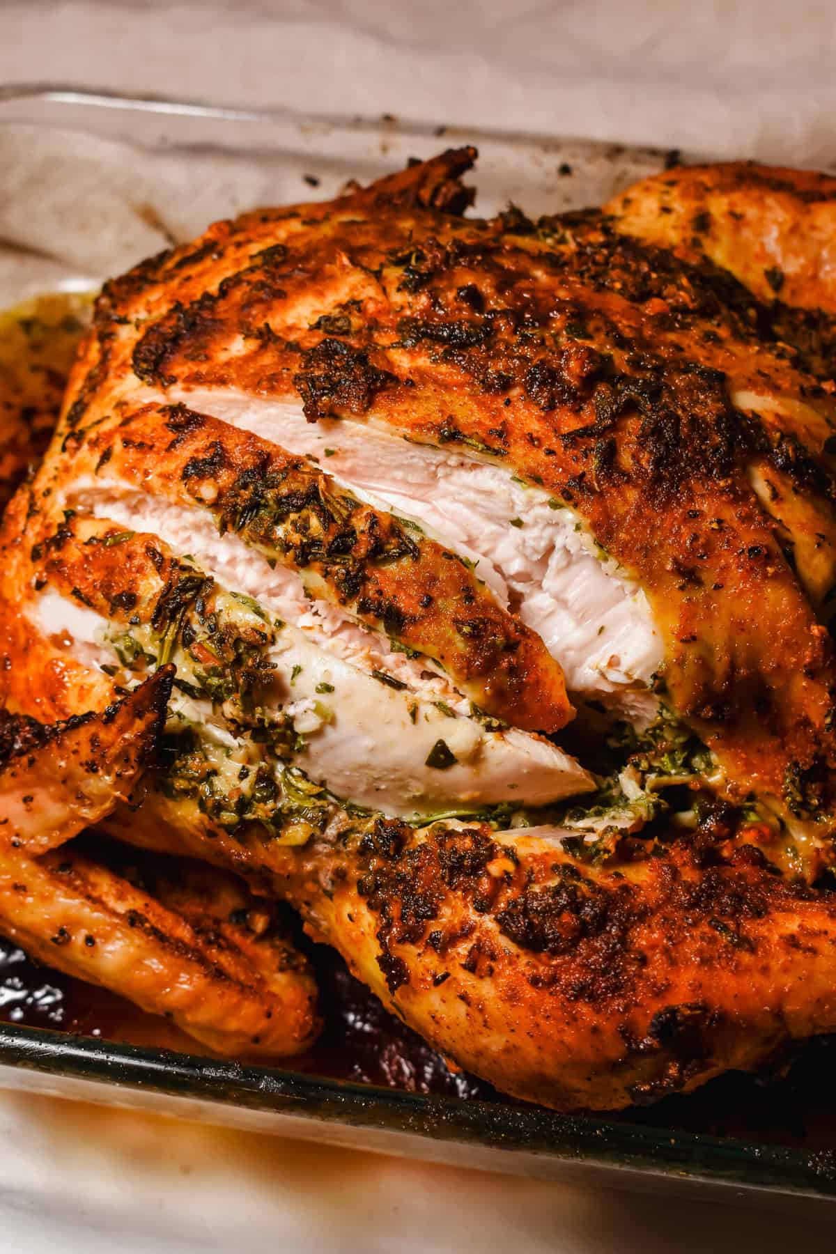 this is a side view close up of my easy garlic herb butter roasted whole chicken with slices in it. 