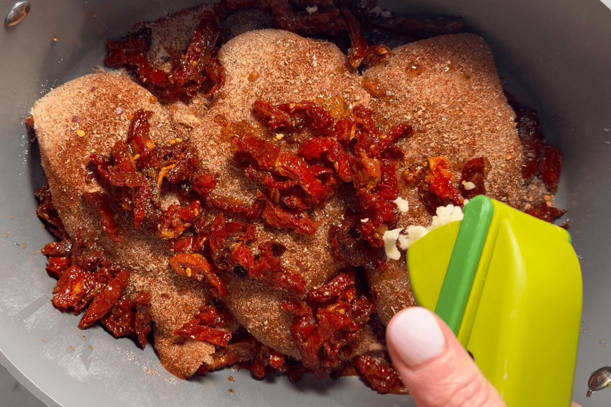 Building the sauce by adding sun-dried tomatoes and bone broth.