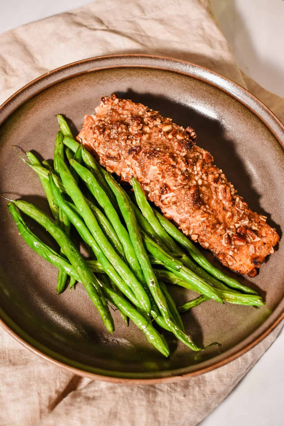side view of the plate of pecan crusted salmon with green bean.