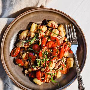 Plated slow cooker balsamic chicken served over gnocchi.