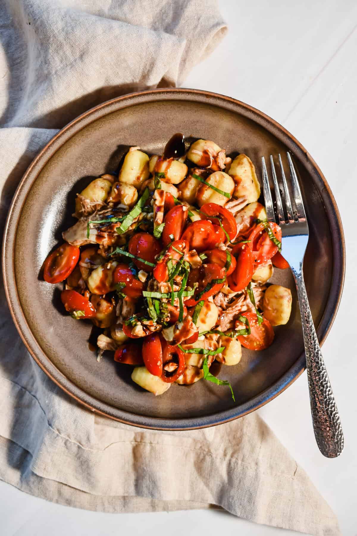A picture of slow cooker balsamic chicken served over gnocchi.