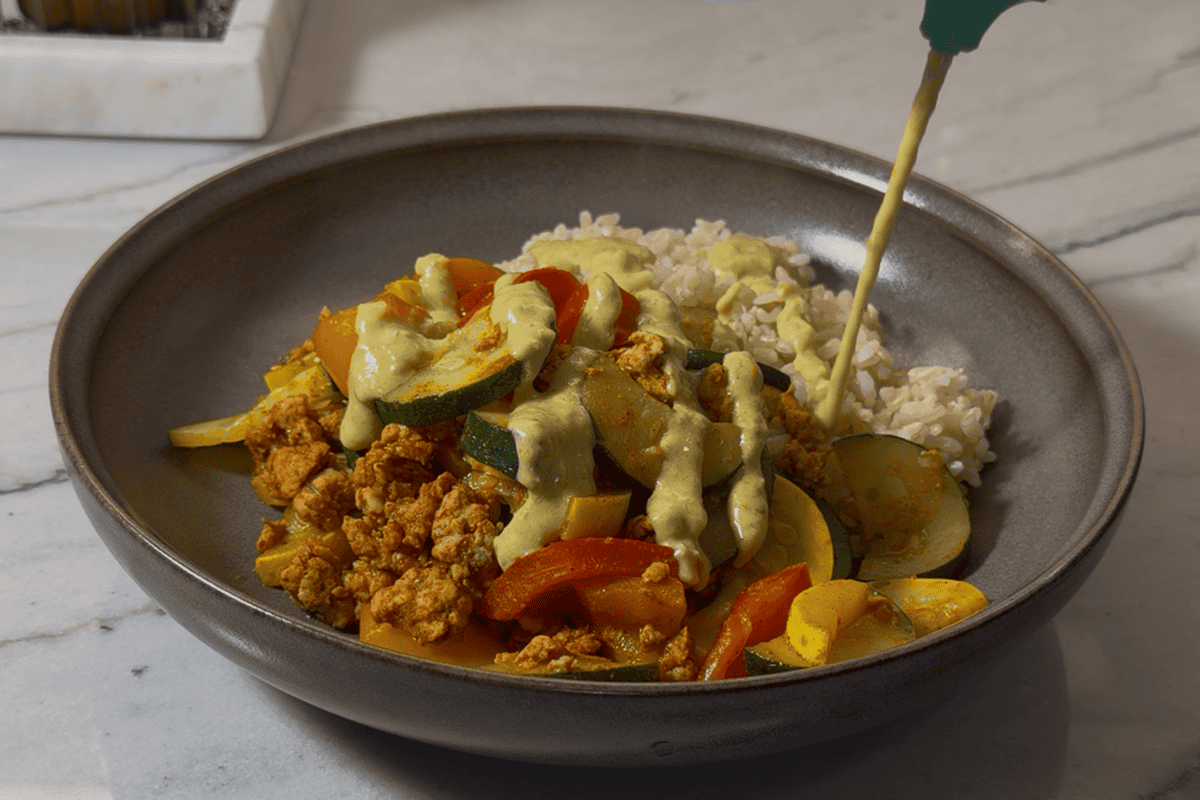 Plating the Mexican stir fry and topping it with creamy jalapeño sauce.