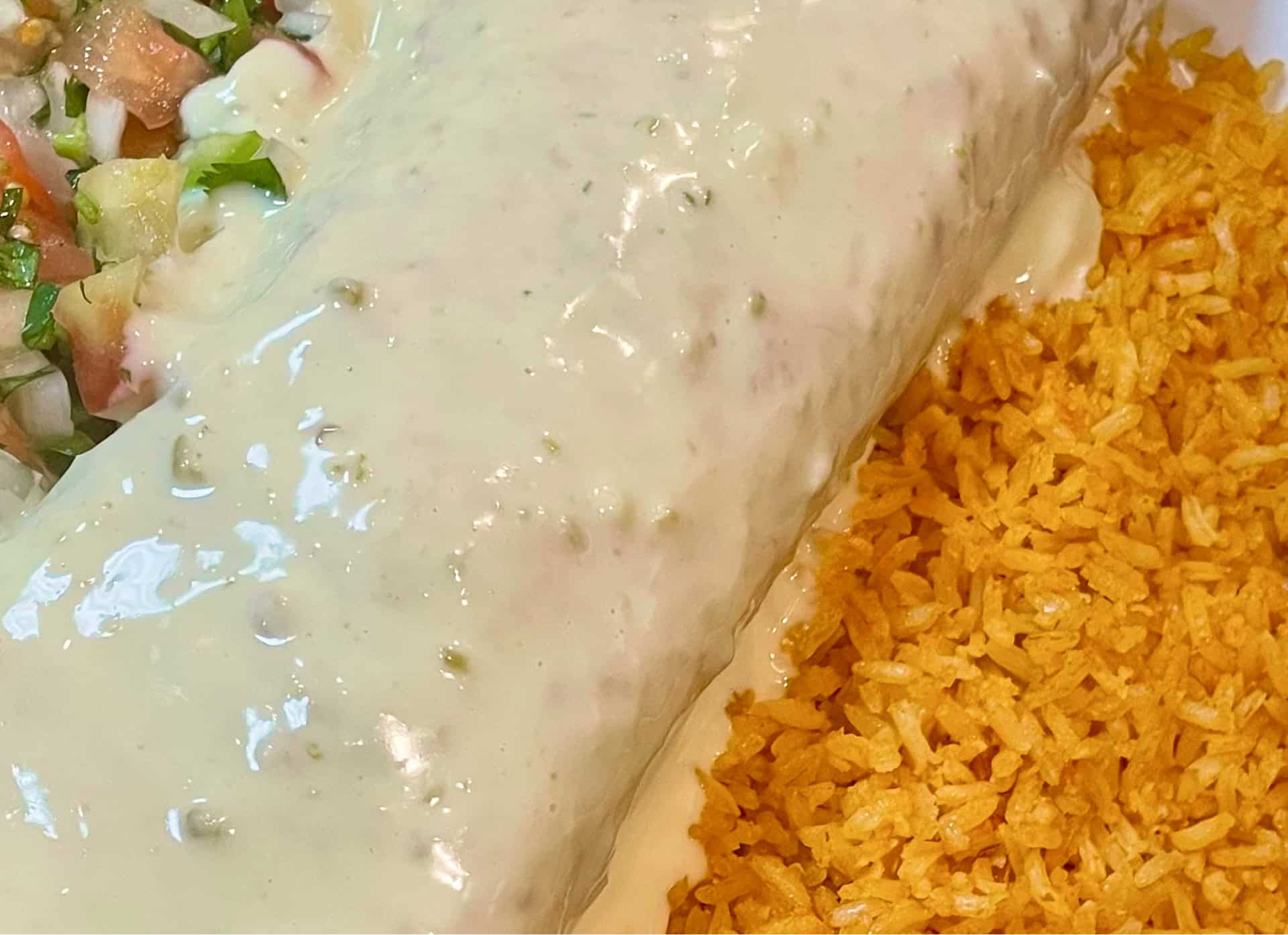 Burrito with rice and creamy sauce, close-up view.