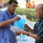 Foto reciente de una persona mayor recibiendo medicamentos en su domicilio, con logo de EsSalud visible.