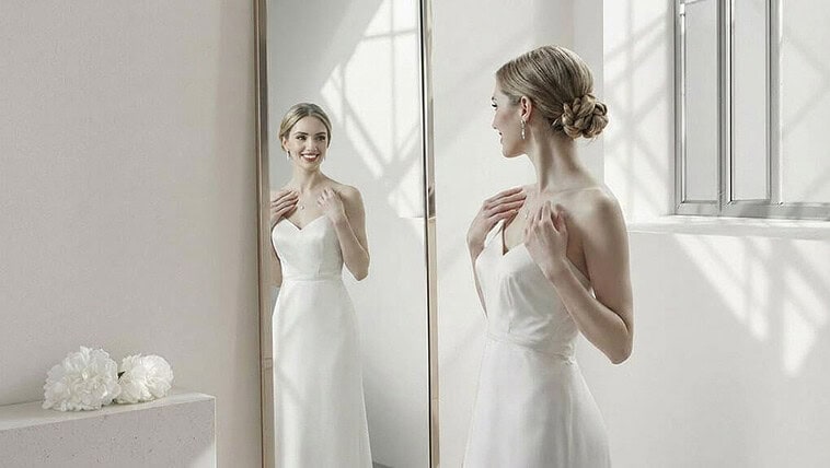 Beautiful bride in elegant wedding dress looking at her reflection.