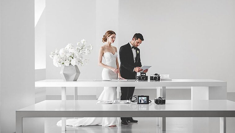 Bride and groom preparing for wedding photoshoot in a modern, bright studio setting.