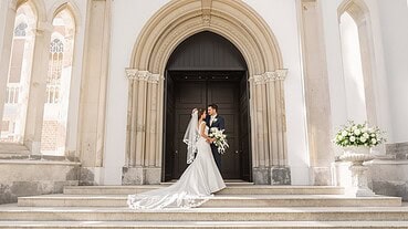Bride and groom sharing a kiss outside a historic church entrance.