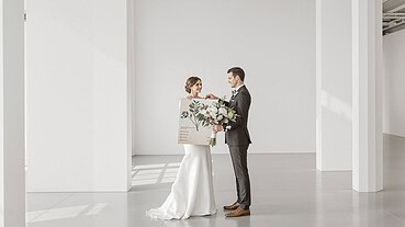 Bride and groom exchanging vows in a sleek, modern wedding venue with natural light.