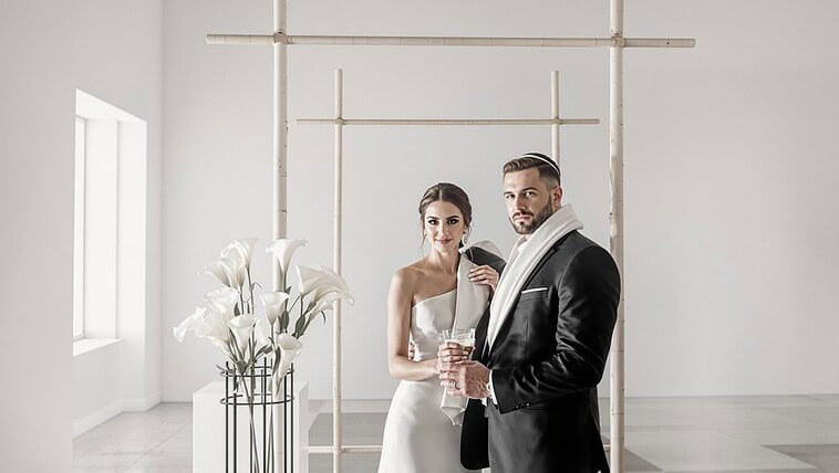 Elegant wedding couple in modern minimalist setting with white flowers.