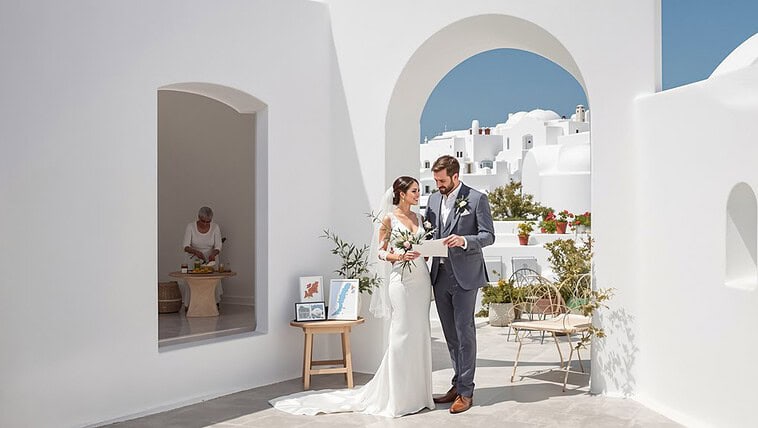 Elegant wedding couple exchanging vows in Santorini's iconic white architecture.