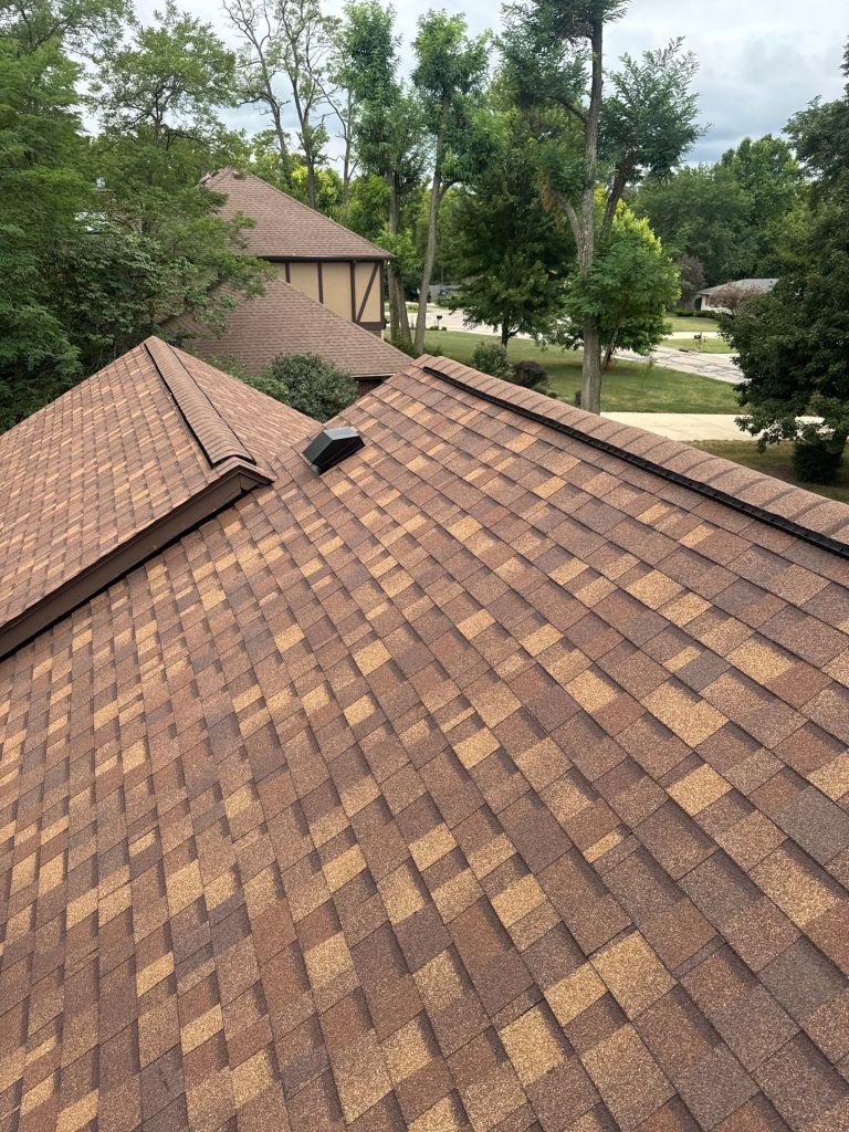 High-quality asphalt shingle roofing with multiple roof pitches and a roof vent for optimal attic ventilation in a residential home.