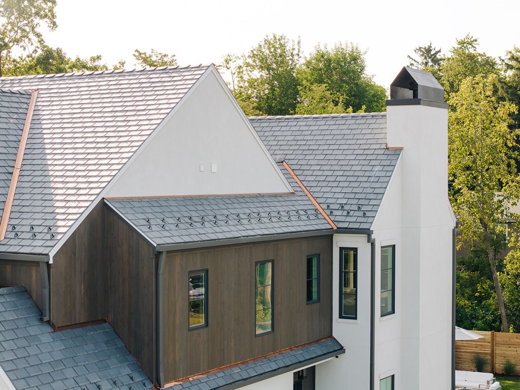 Metal and asphalt shingle roofing with modern siding, metal chimney cap, and large windows on contemporary house - best roofing and siding services.
