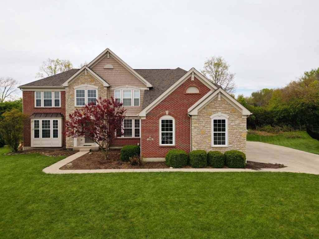 Two-story brick and stone home featuring expert Roofing & Siding Installation Services for improved curb appeal and protection.