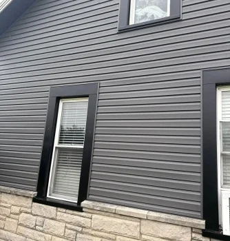 New gray vinyl siding with black window trims on a residential home.
