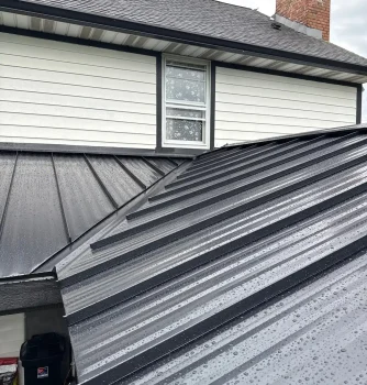 Metal roof panels with rain droplets on a residential house, showcasing durable roofing solutions.
