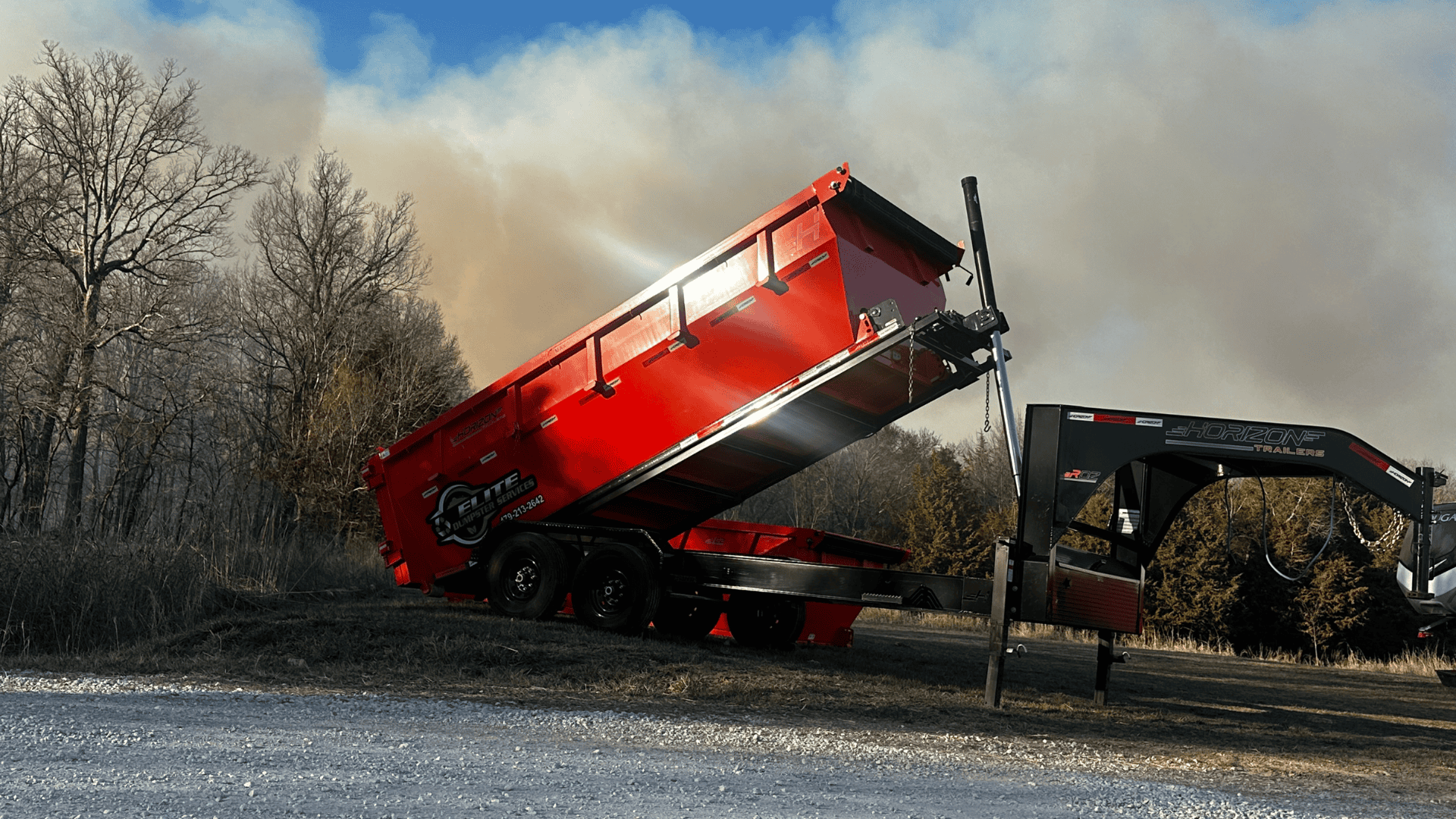 Red dump trailer with hydraulic lift for construction debris.